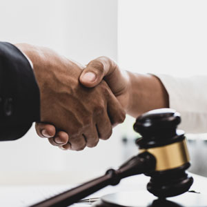 Handshake between attorney and client with gavel symbolizing business litigation - Schneider Law, P.C.